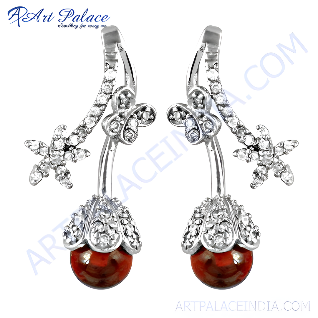 Silver drop earrings with red gemstone, a floral design on a white background.